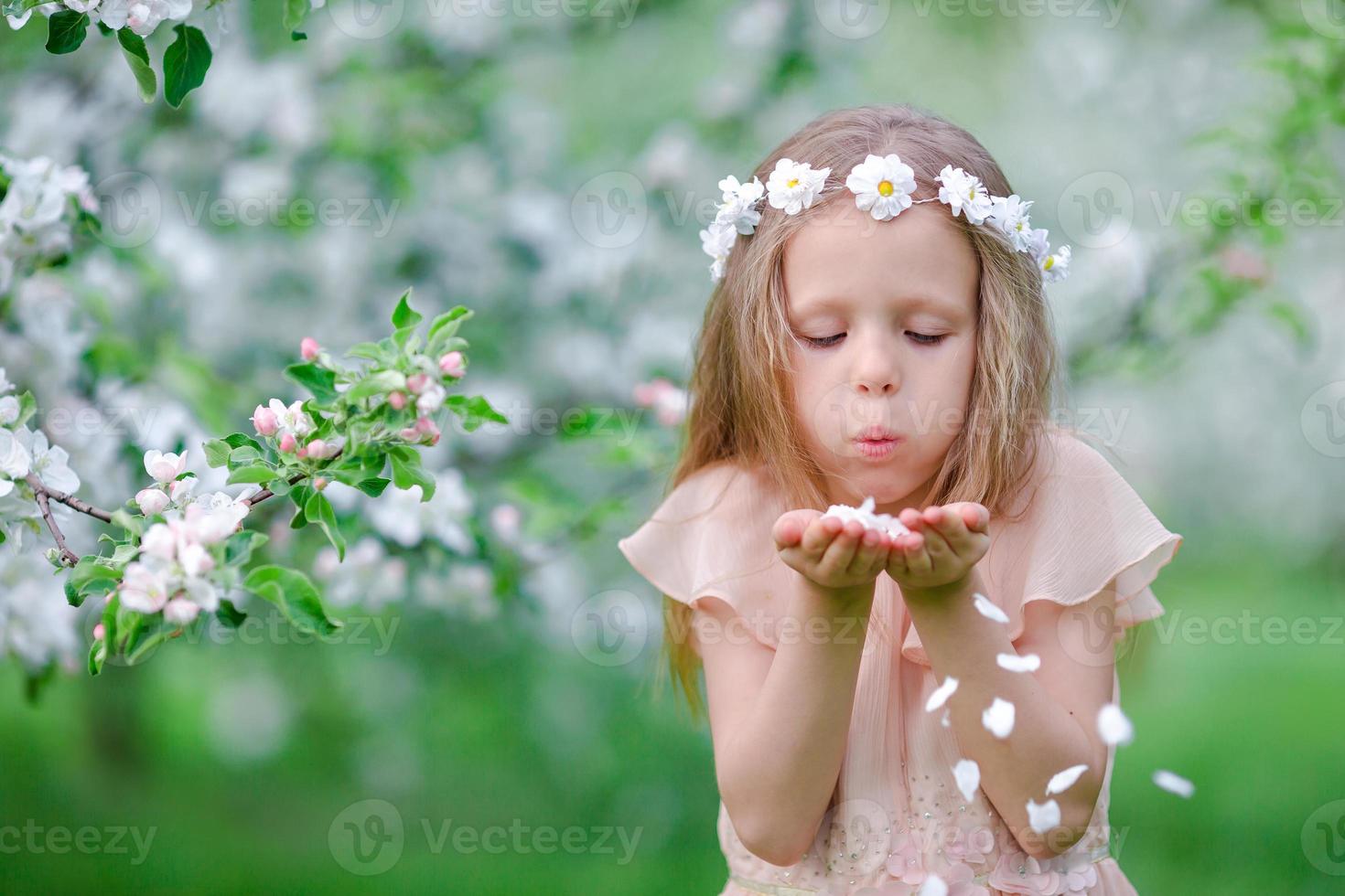 Adorable little girl in blooming tree garden on spring day photo