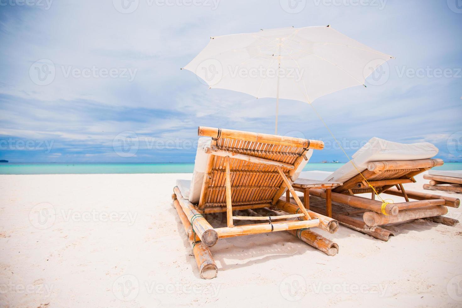 Beach beds and umbrellas on exotic tropical white sandy beach photo