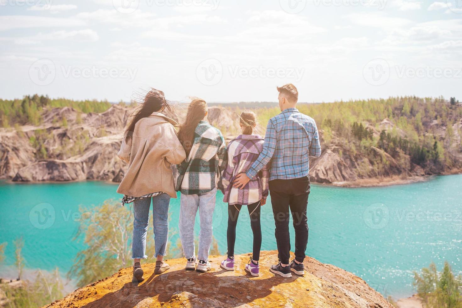 Young parents and kids hiking in mountains. Beautiful view of blue lake photo