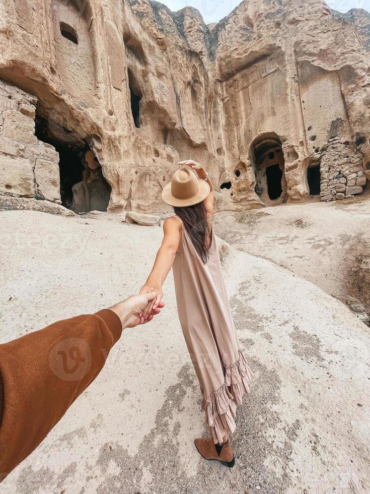 Happy young woman on background of ancient cave formations in Cappadocia, Turkey. The Monastery is one of the largest religious buildings. photo