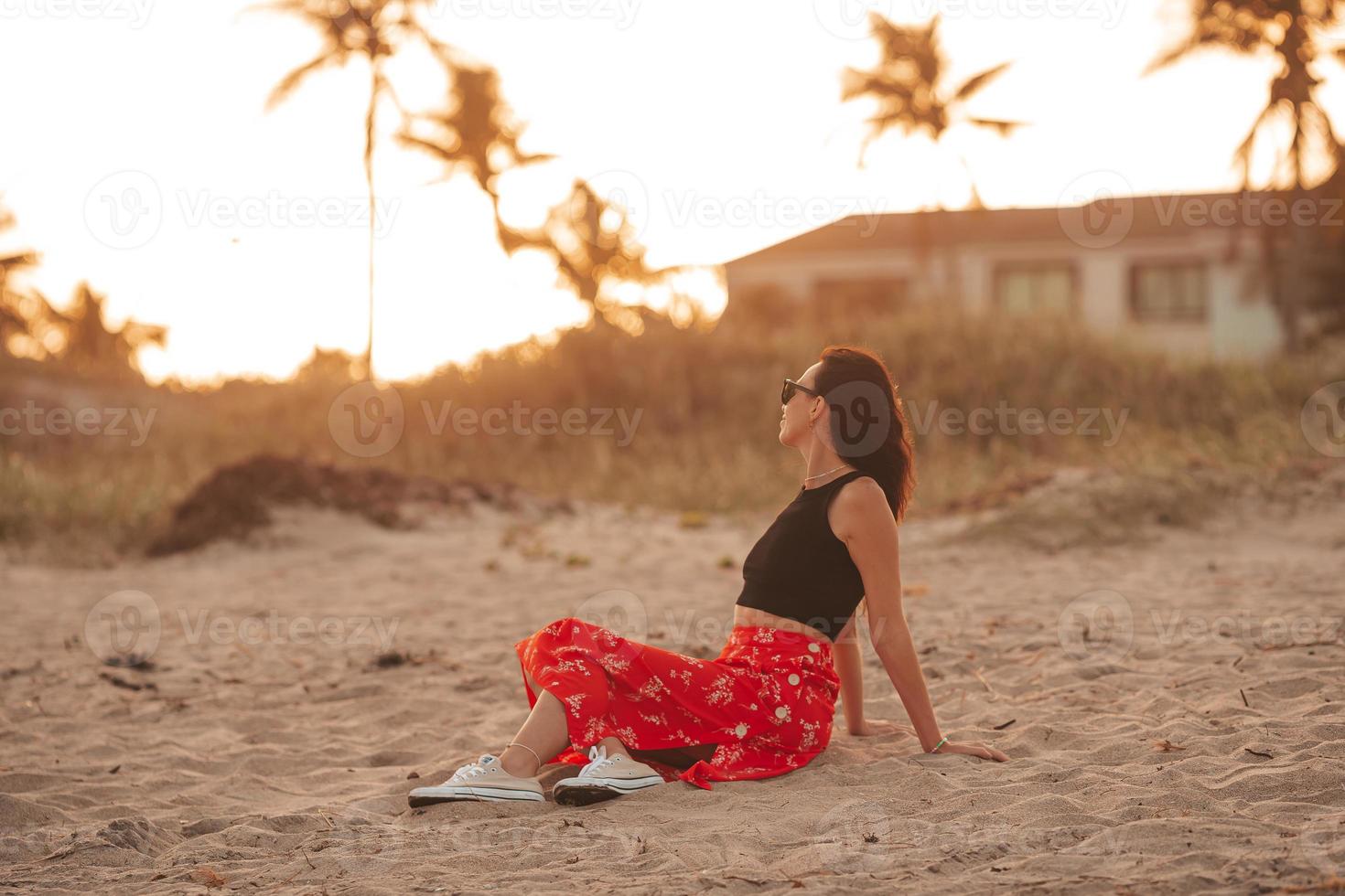 mujer feliz disfrutando de la hermosa puesta de sol en la playa foto
