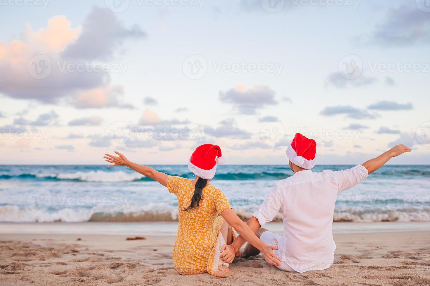 pareja feliz de navidad en sombreros de santa en vacaciones en la playa foto