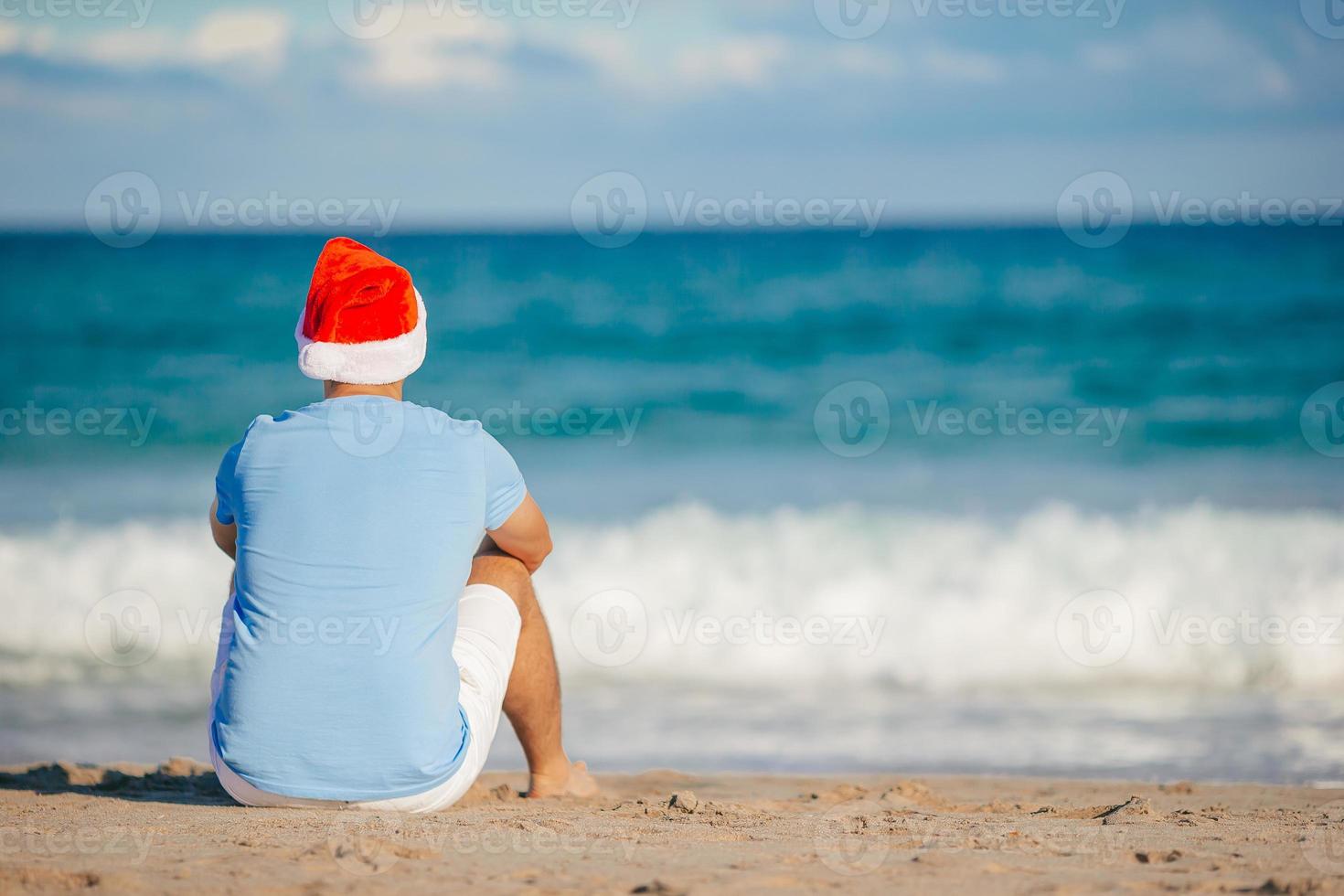 Young man in Santa hat on Christmas beach holidays photo