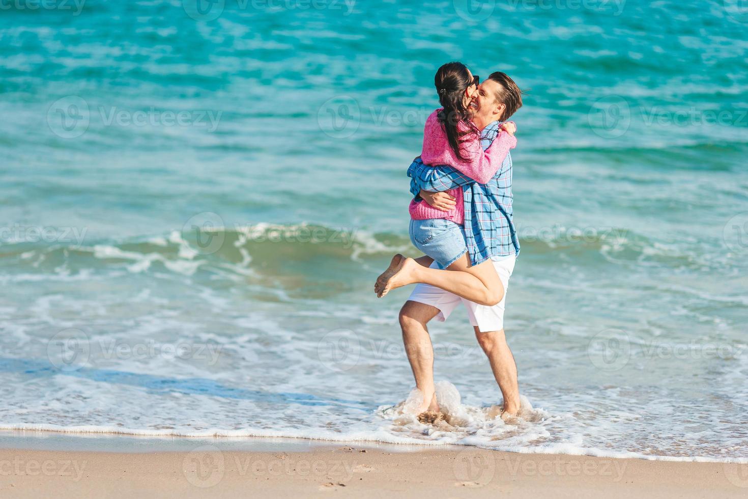 Young couple having fun on the beach splashing in shallow water photo