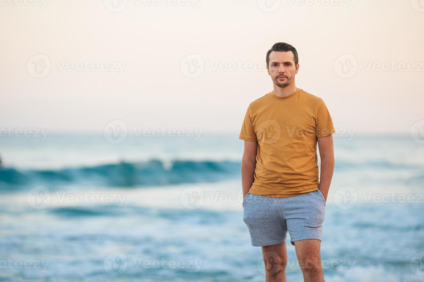 Young man walking on the beach at sunset photo