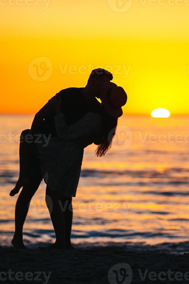 Romantic couple on the beach at colorful sunset on background photo