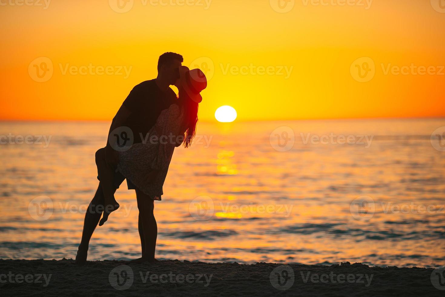 la familia joven disfruta de la luna de miel al atardecer en la playa foto