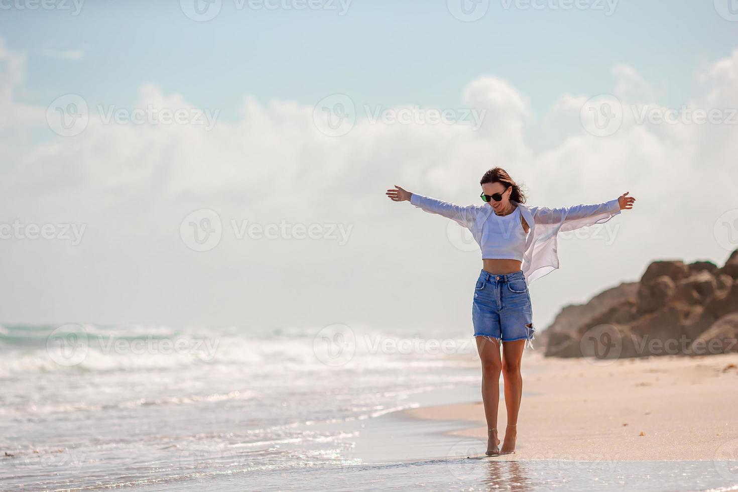 Young happy woman on the beach enjoy her summer vacation. Girl is happy and calm in her stay on the beach photo