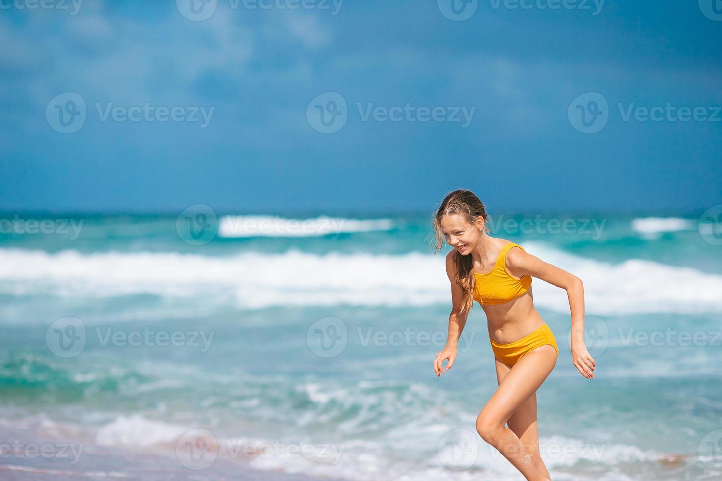 Little happy girl splashing and running in clear turquoise water photo