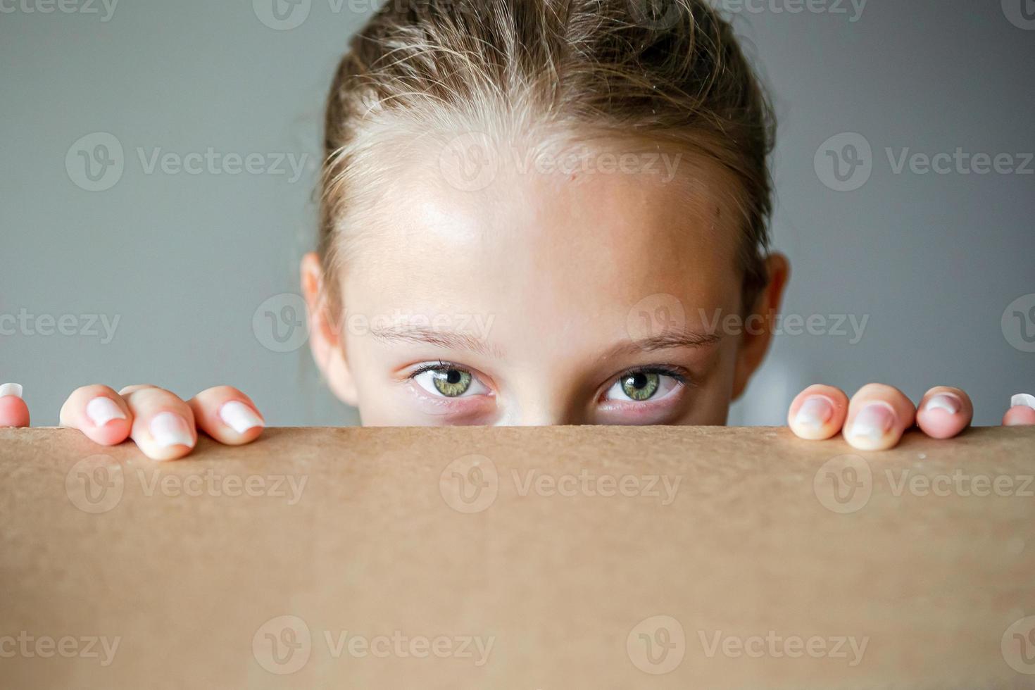 Happy girl with beautiful green eyes in new house with cardboard box photo