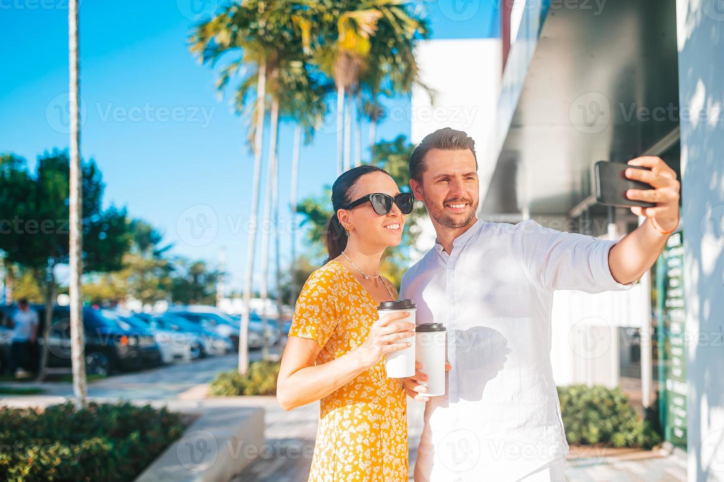 pareja joven con café para ir a la calle en la ciudad de verano tomando selfie foto