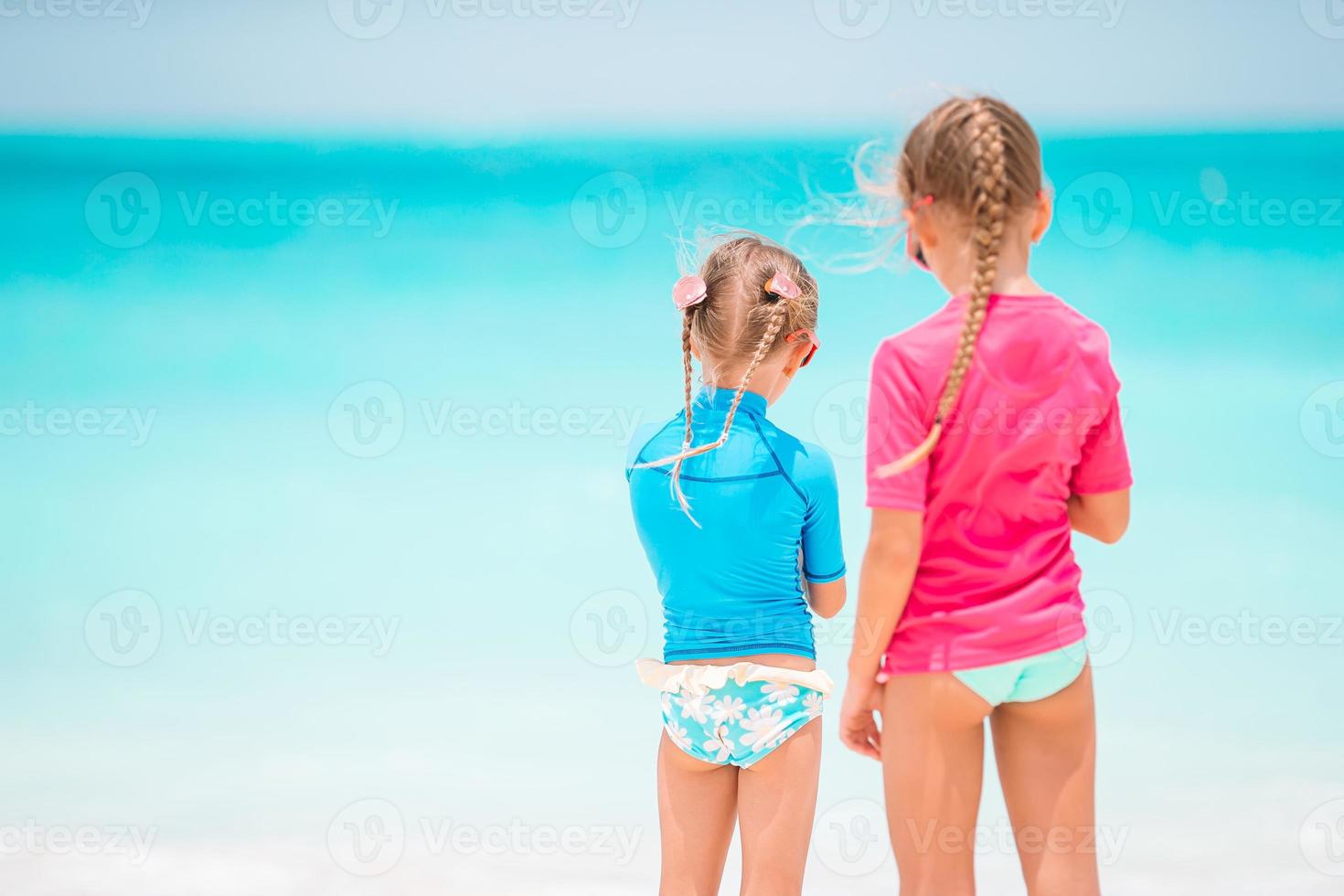 Little happy funny girls have a lot of fun at tropical beach playing together. photo