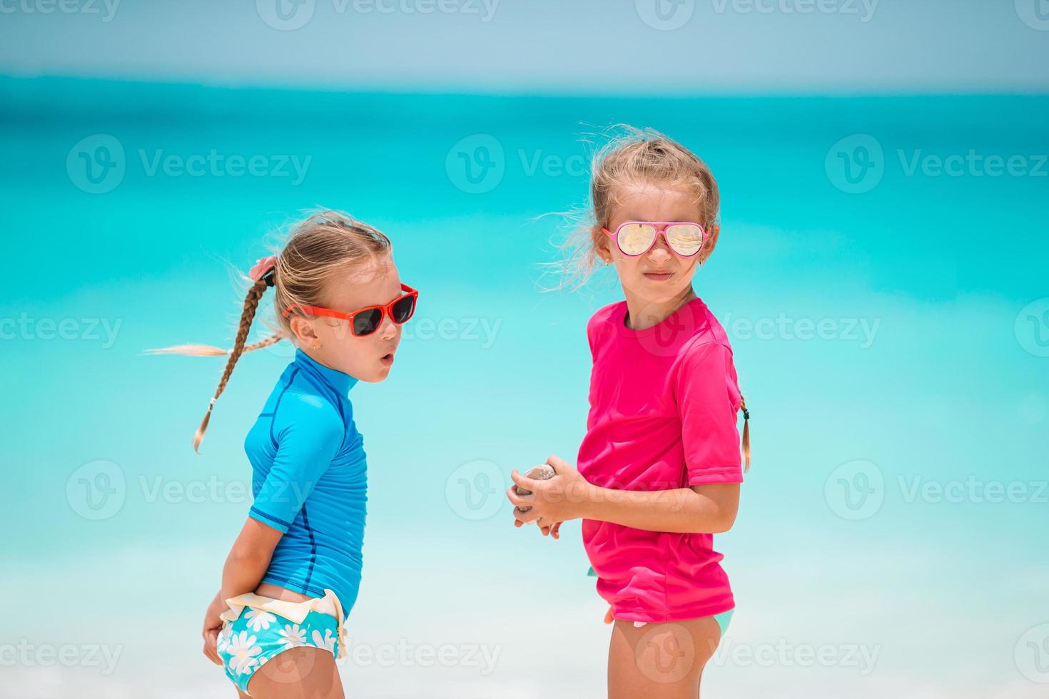 Little girls having fun at tropical beach playing together at shallow water photo