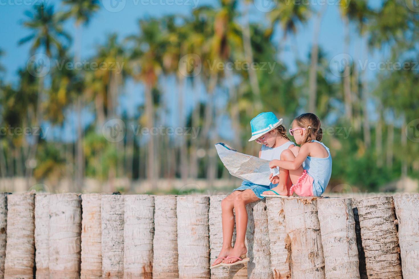 Adorable little girls with big map of island on beach photo