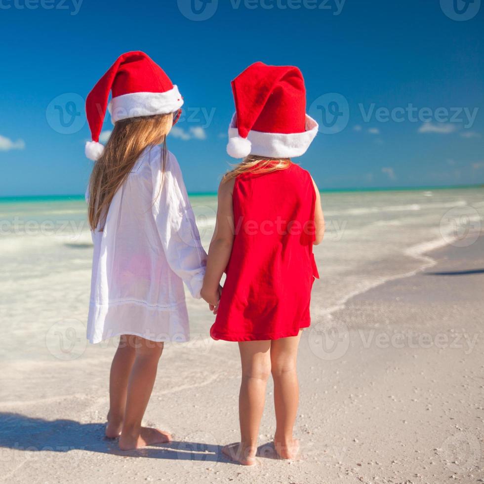 niñas lindas con sombreros de navidad en la playa exótica foto