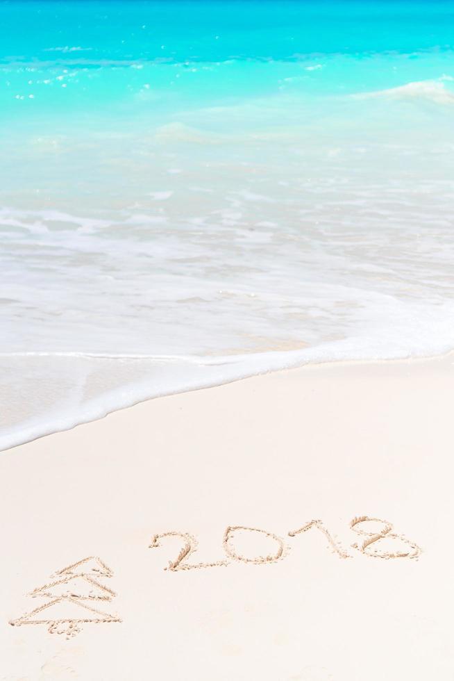 2018 handwritten on sandy beach with soft ocean wave on background photo