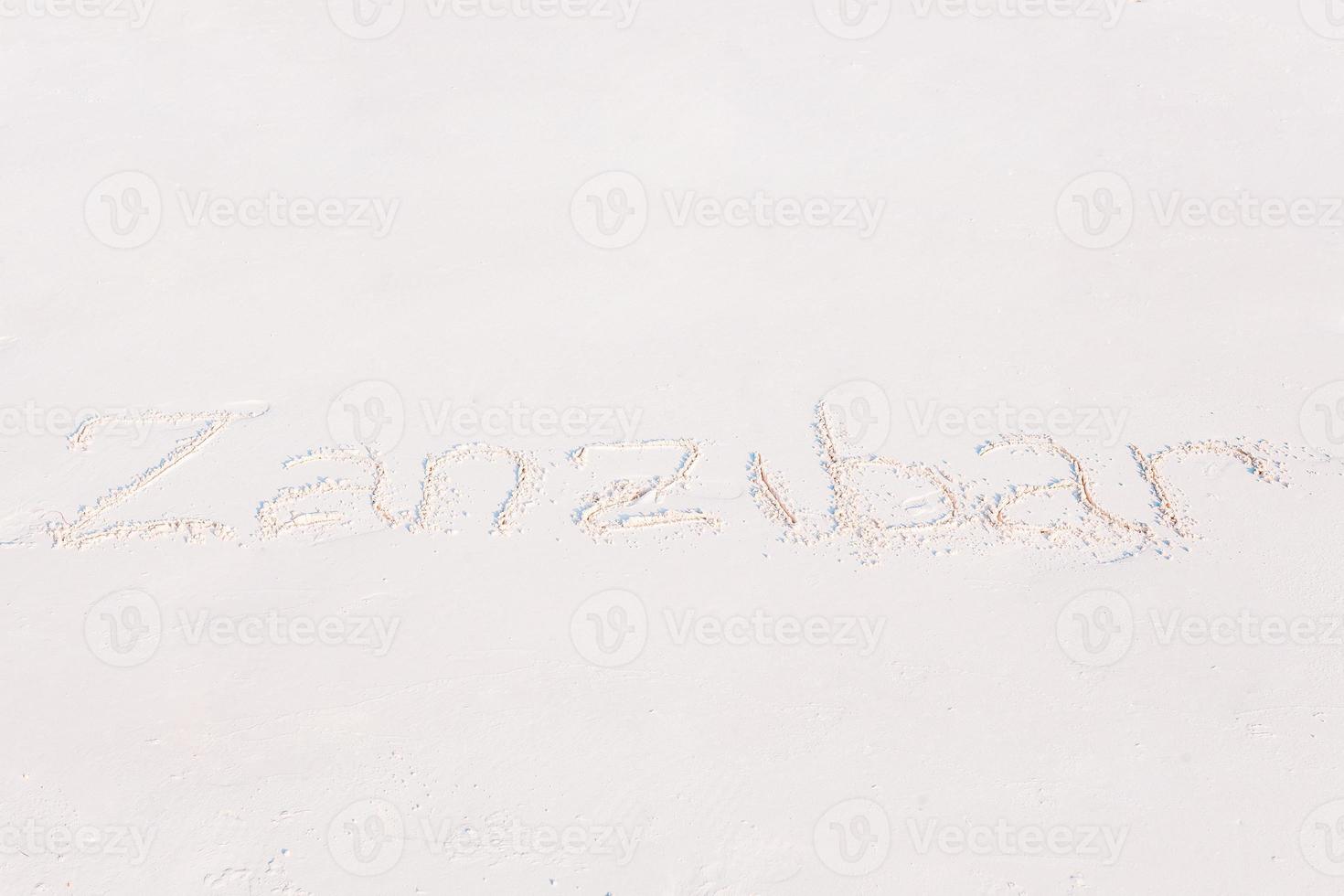 Word handwritten on sandy beach with soft ocean wave on background photo