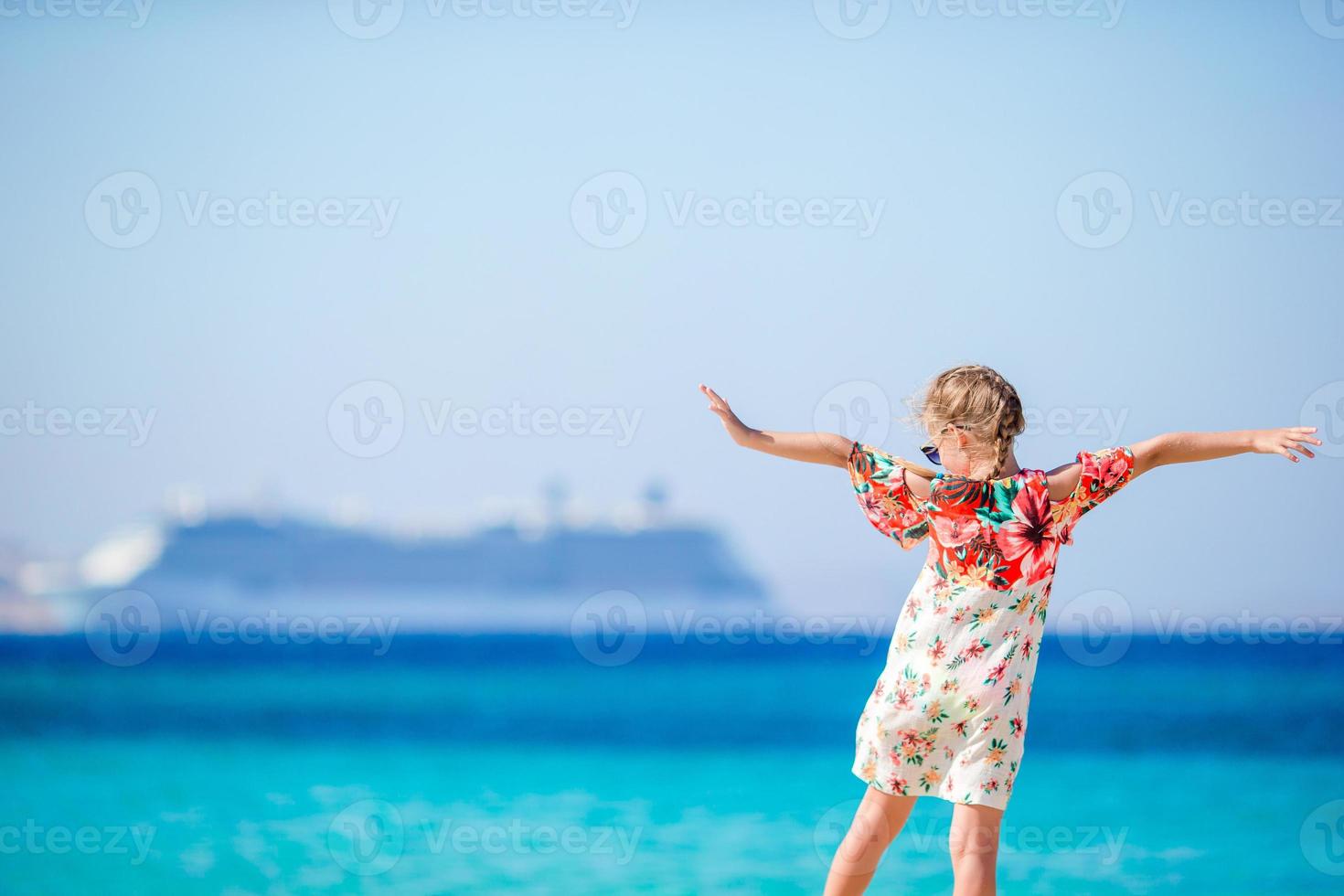 Adorable little girl at beach background big cruise lainer in Greece photo