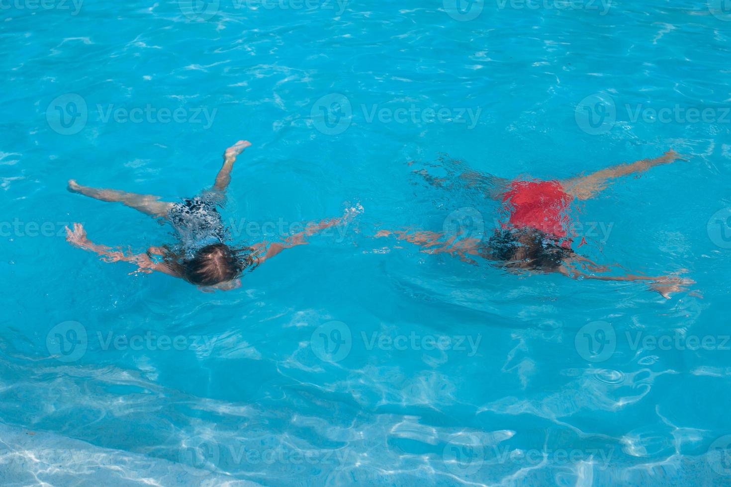 Little adorable girls swimming in the swimmingpool photo