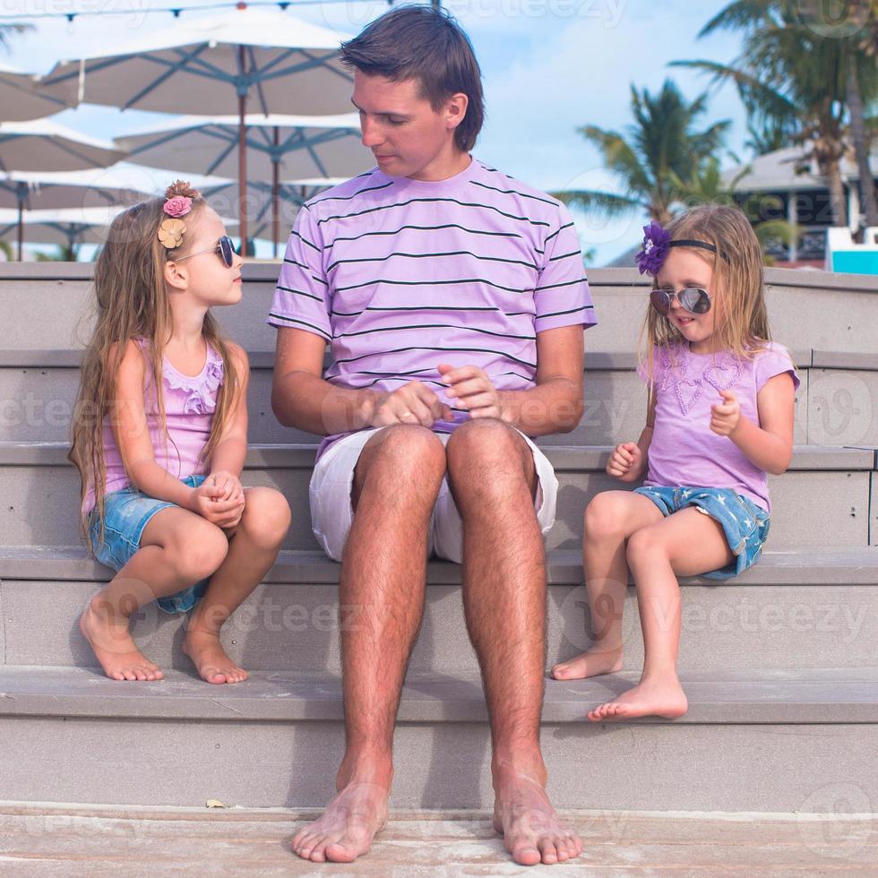 Family of three sitting on wooden dock enjoying ocean view photo