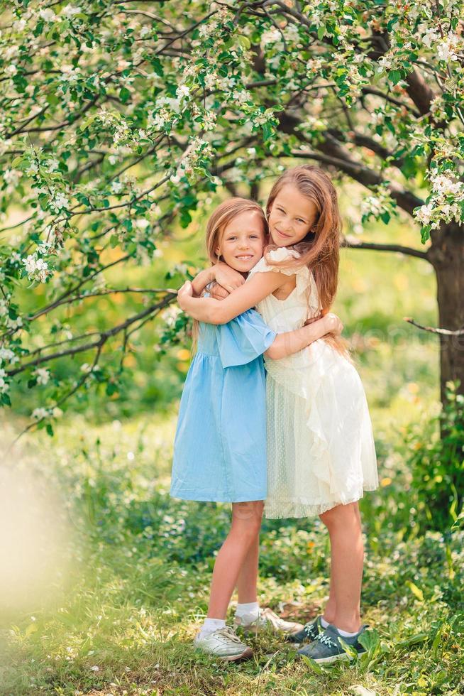 niñas adorables en el floreciente jardín de manzanos el día de primavera foto