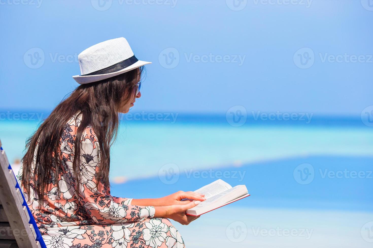 Young woman reading book during tropical white beach photo