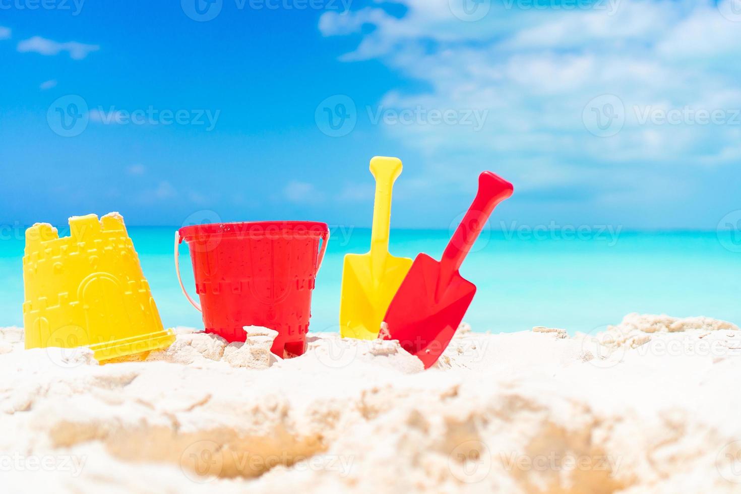 Kid's beach toys and straw hat on white sandy beach photo