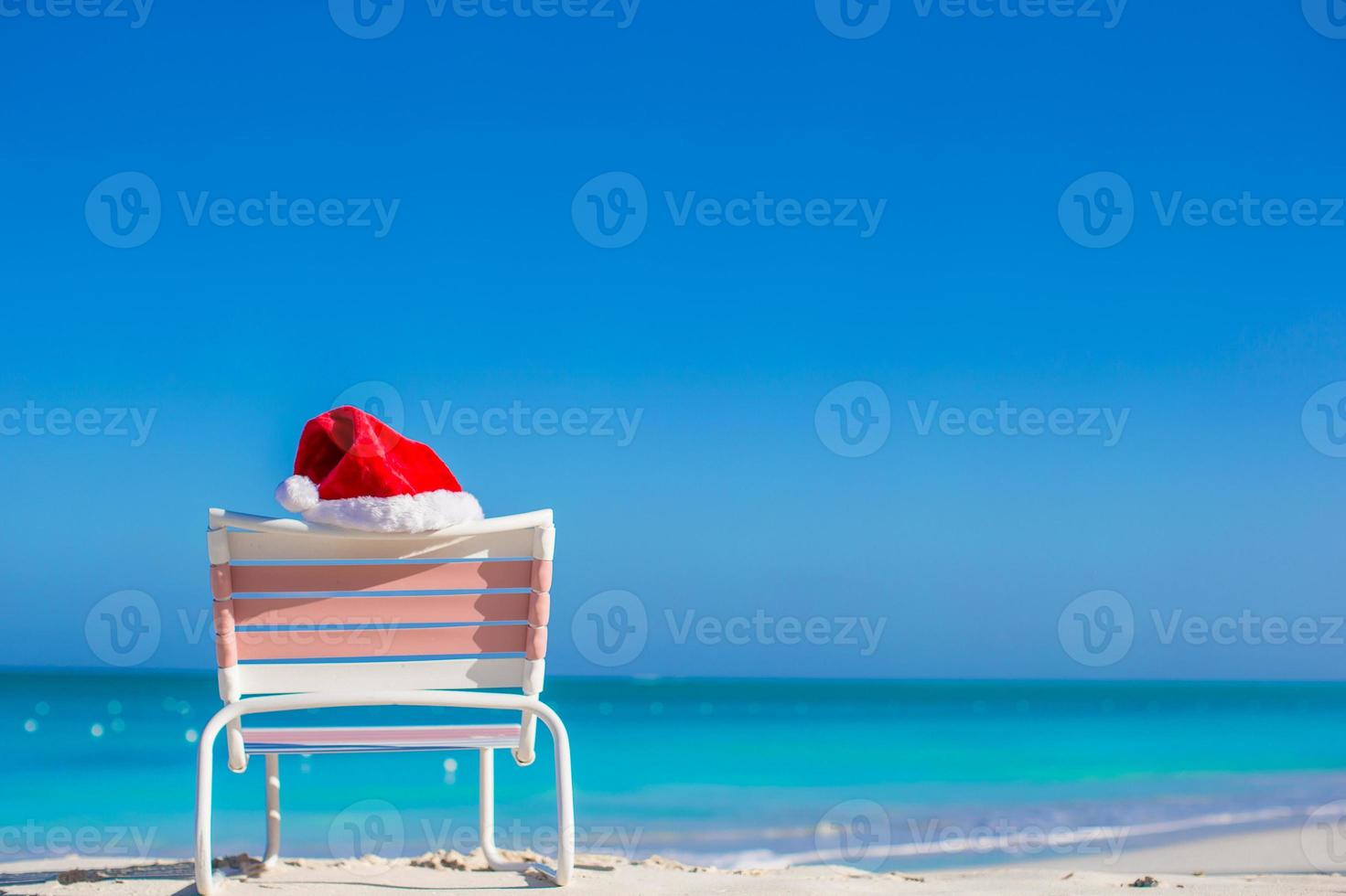 Red Santa hat on chair longue at sea shore photo