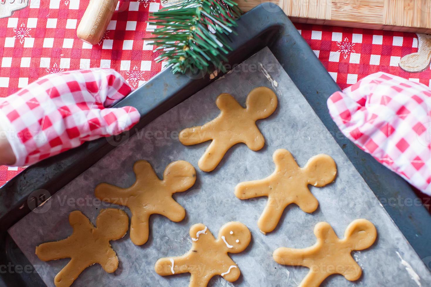 Raw gingerbread men with glaze on a baking sheet photo