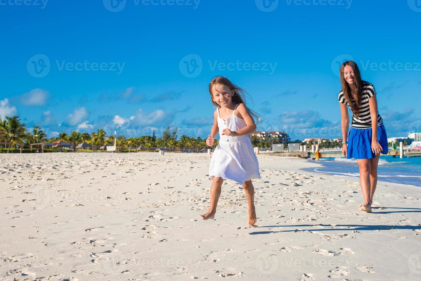Mother and her little daughter having fun at exotic beach on sunny day photo