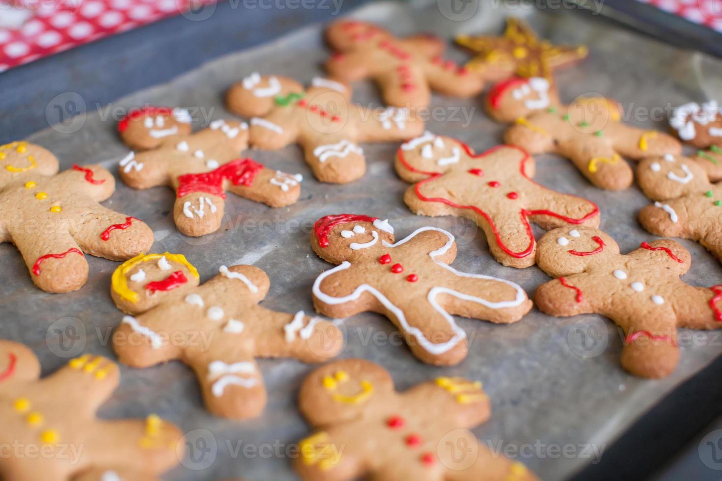 Raw gingerbread men with glaze on a baking sheet photo