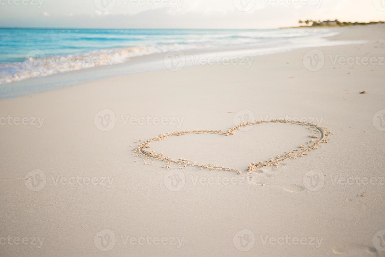 Heart painted in white sand on a tropical beach photo