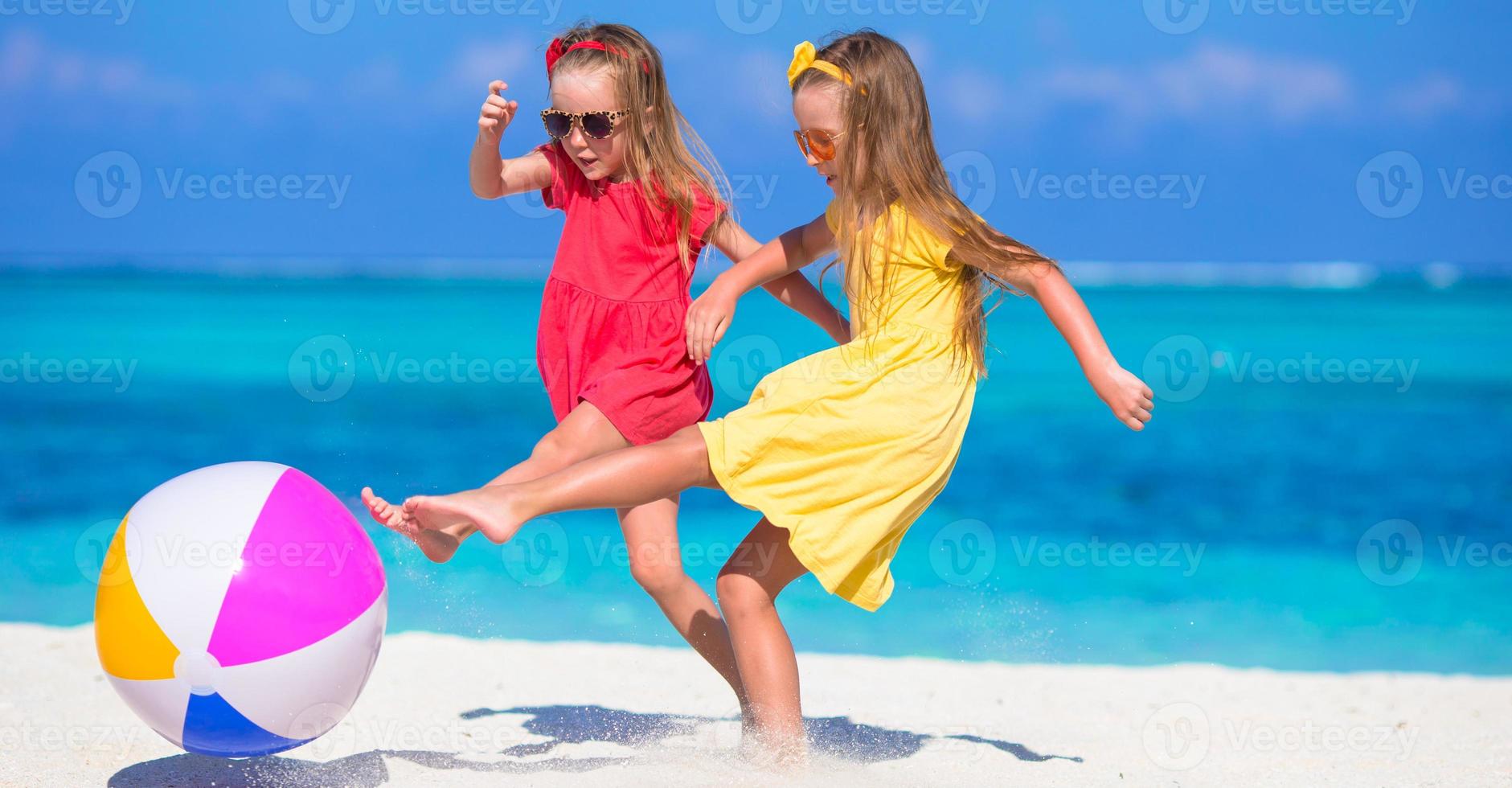 Little adorable girls playing on beach with air ball photo