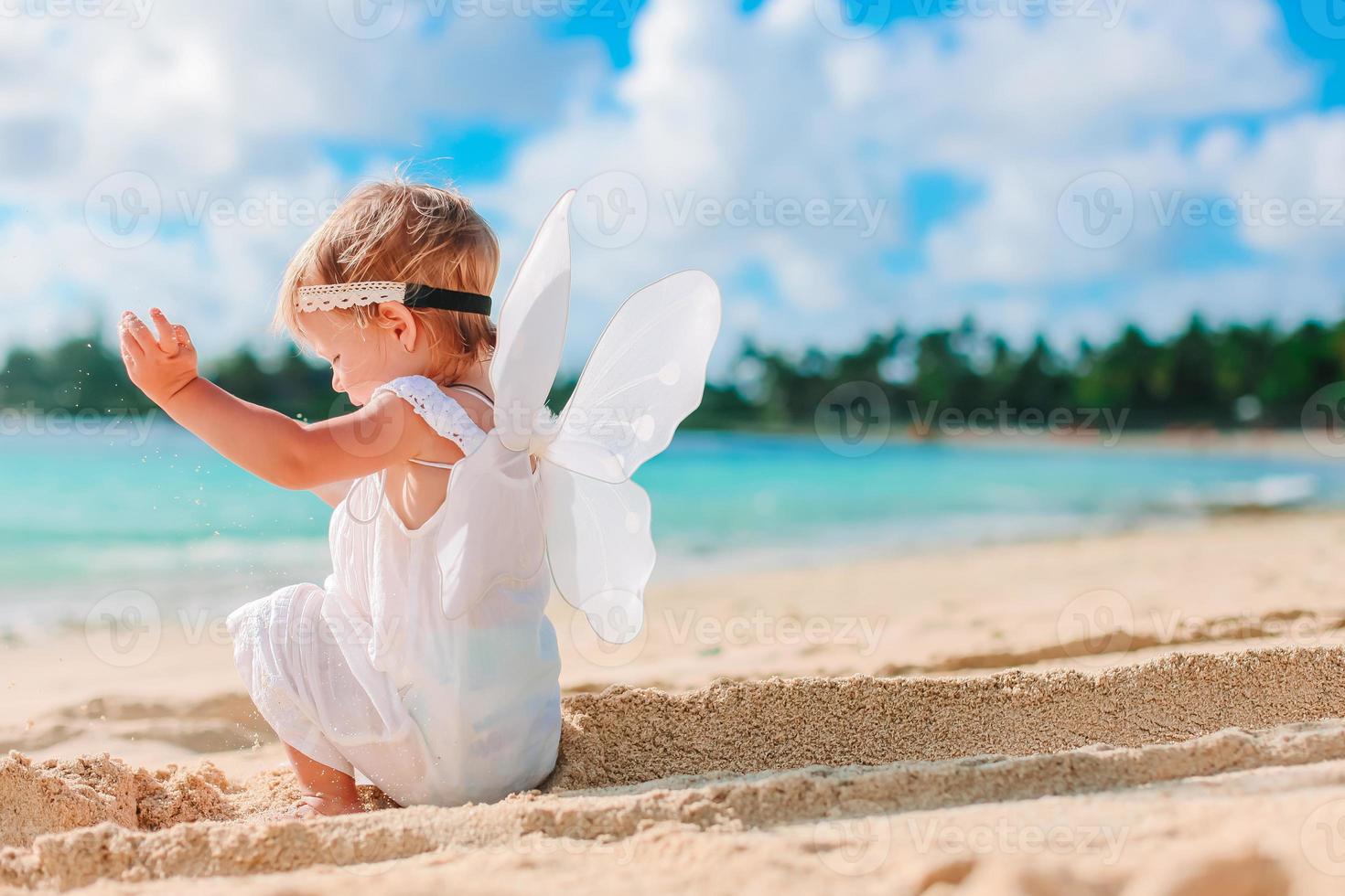 Beautiful young girl wearing angel wings on the beach photo