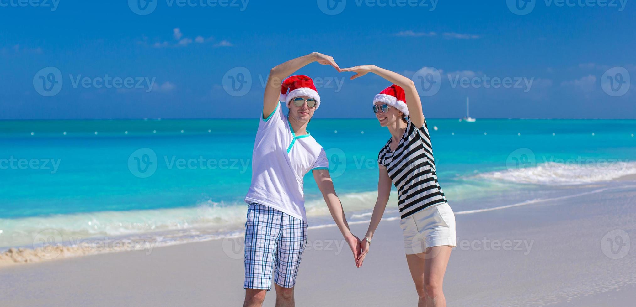 Portrait of young couple in Santa hats enjoy beach vacation photo
