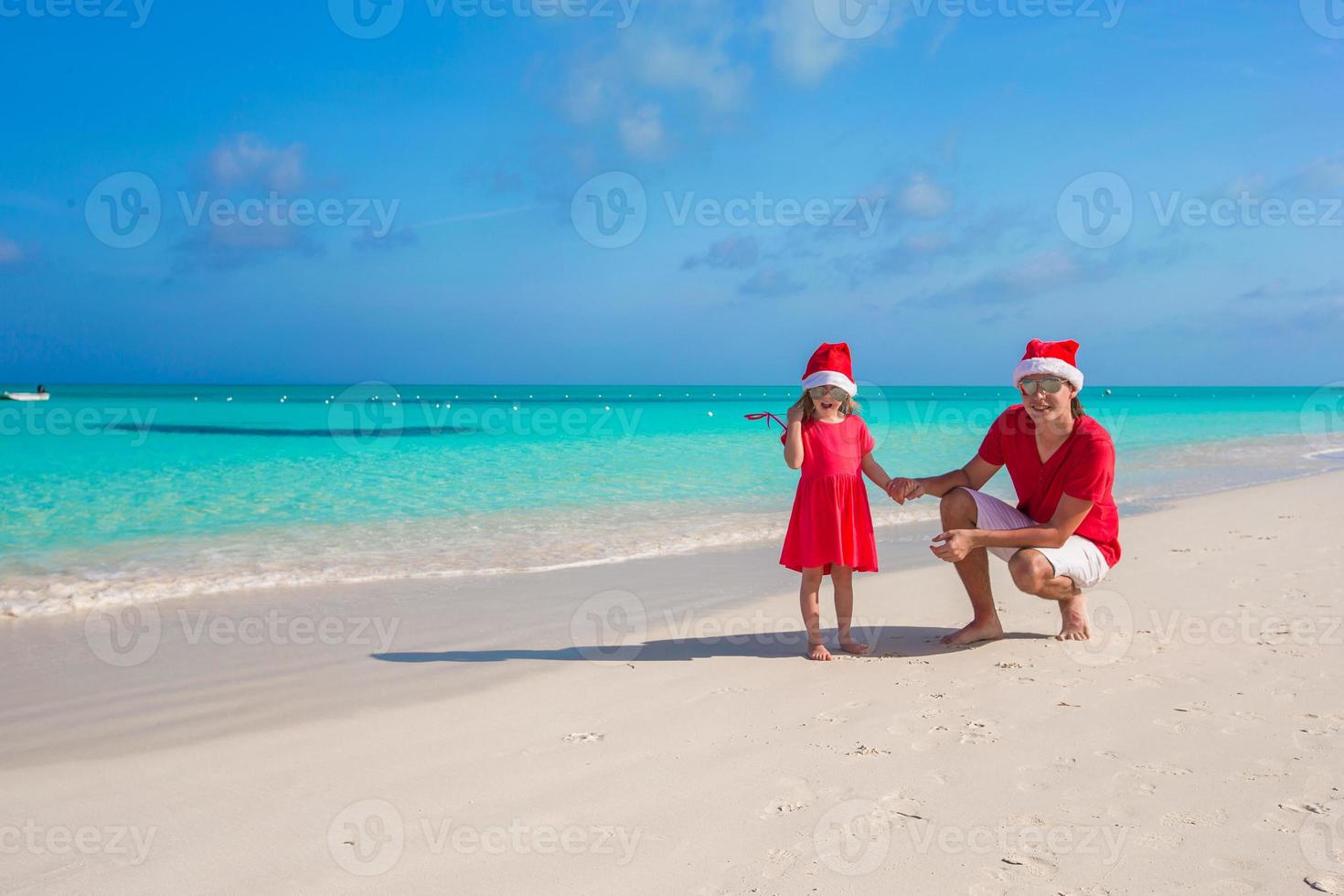 Niña y papá feliz en santa hat en playa exótica foto