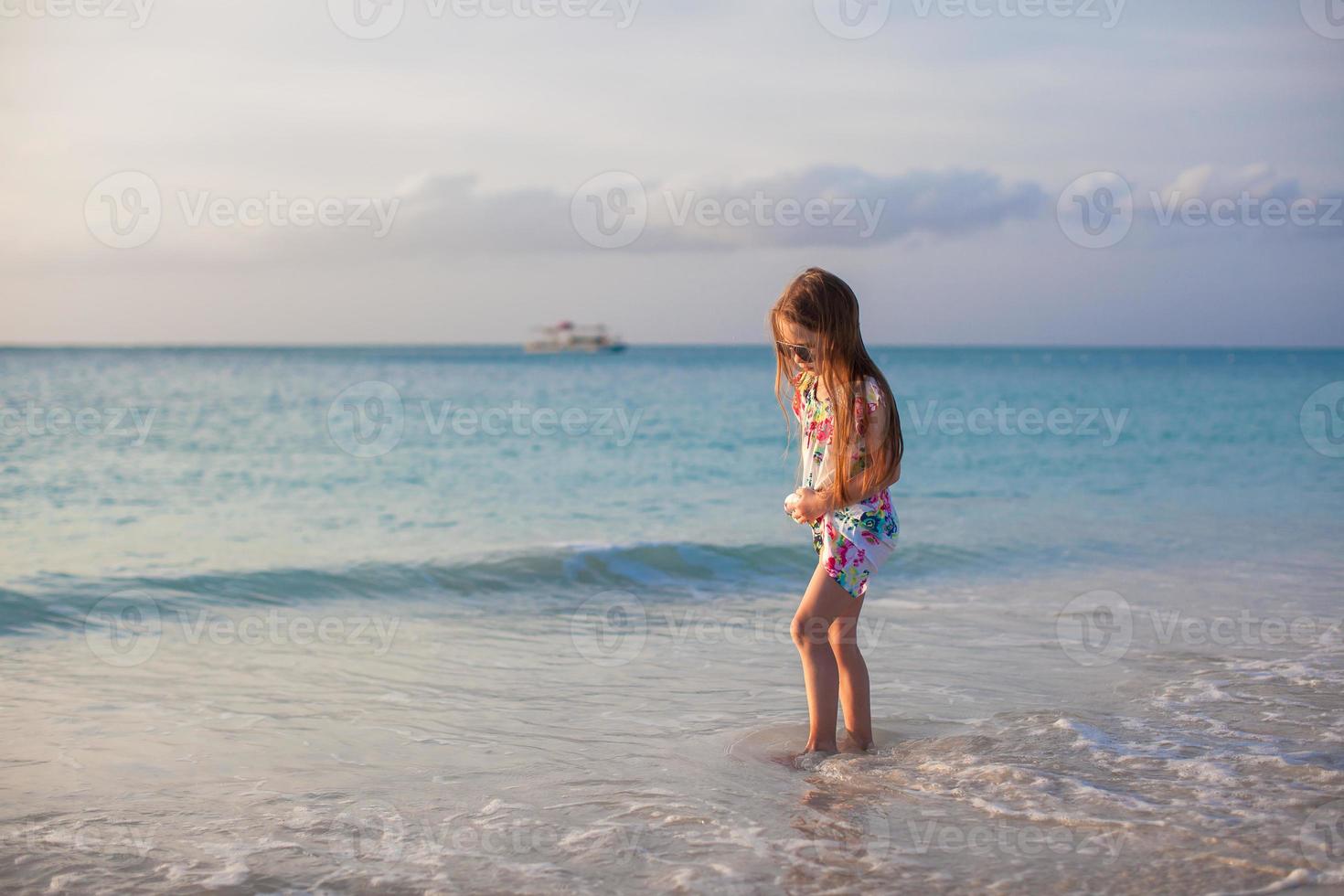 Adorable little girl walking at white tropical beach photo