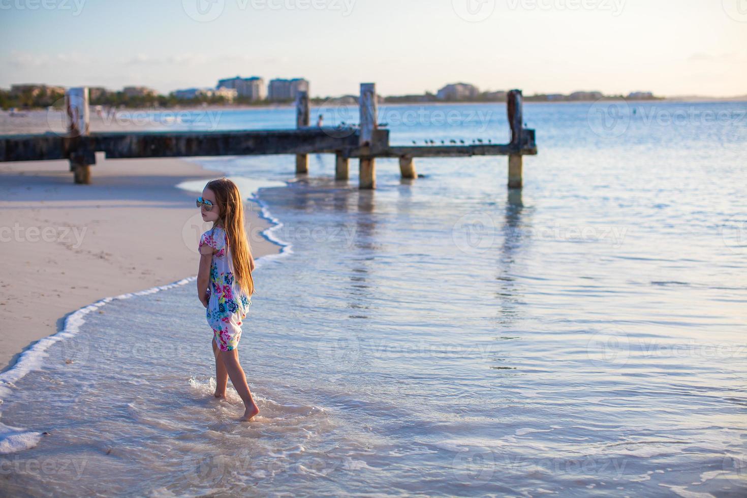 Adorable little girl walking at white tropical beach photo