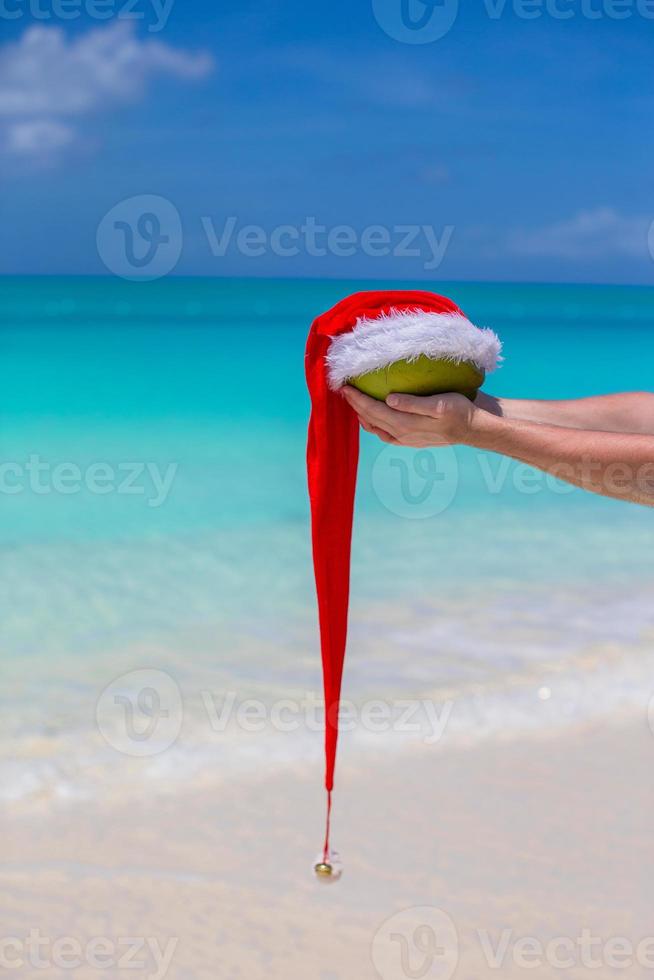 coco con sombrero de santa en manos masculinas contra el mar turquesa foto