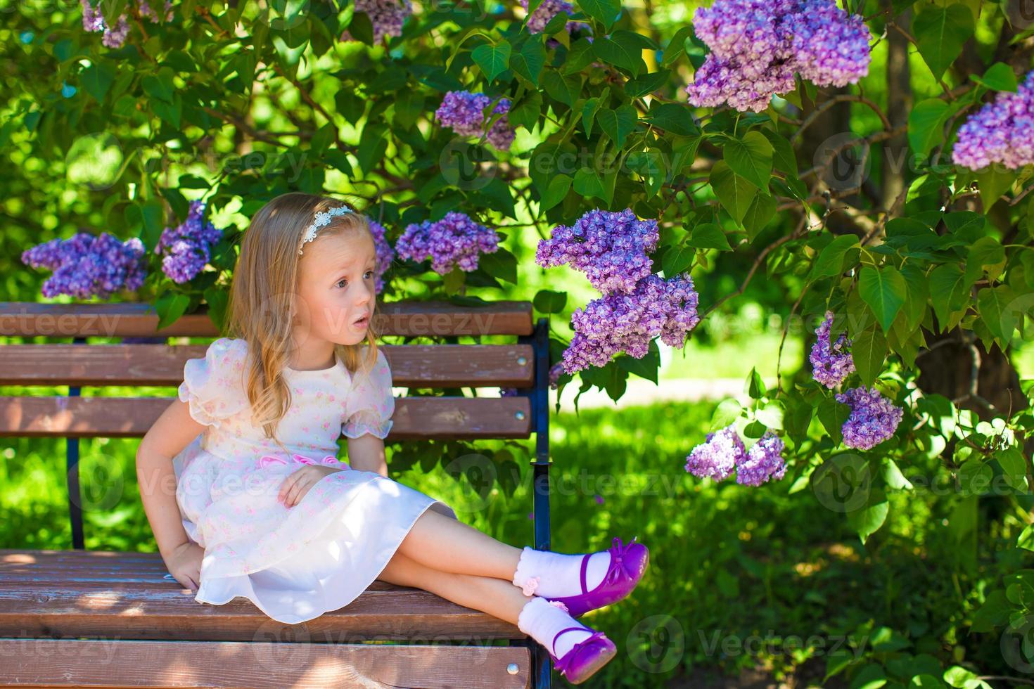 Little adorable girl near flowers in the garden photo