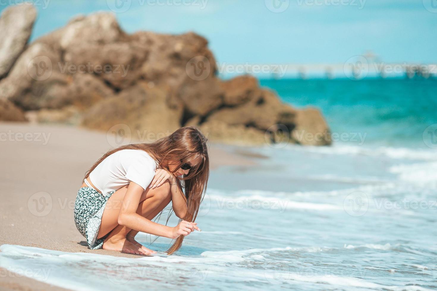 Adorable teen girl has fun at tropical beach during vacation photo