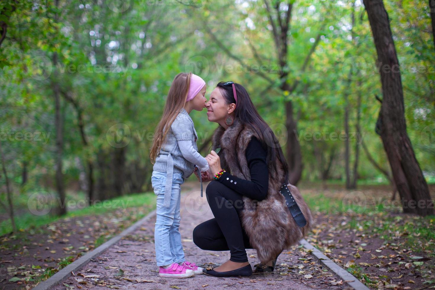 Cute little girl kissing her mother's nose photo