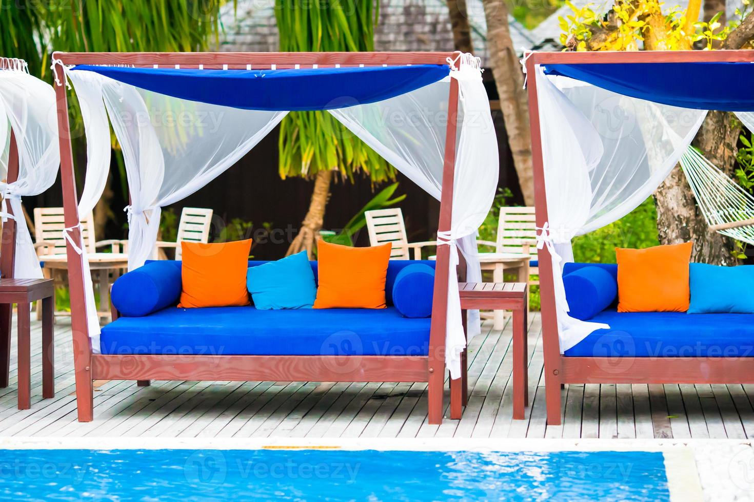 Blue towels on beach beds near swimming pool at tropical resort photo