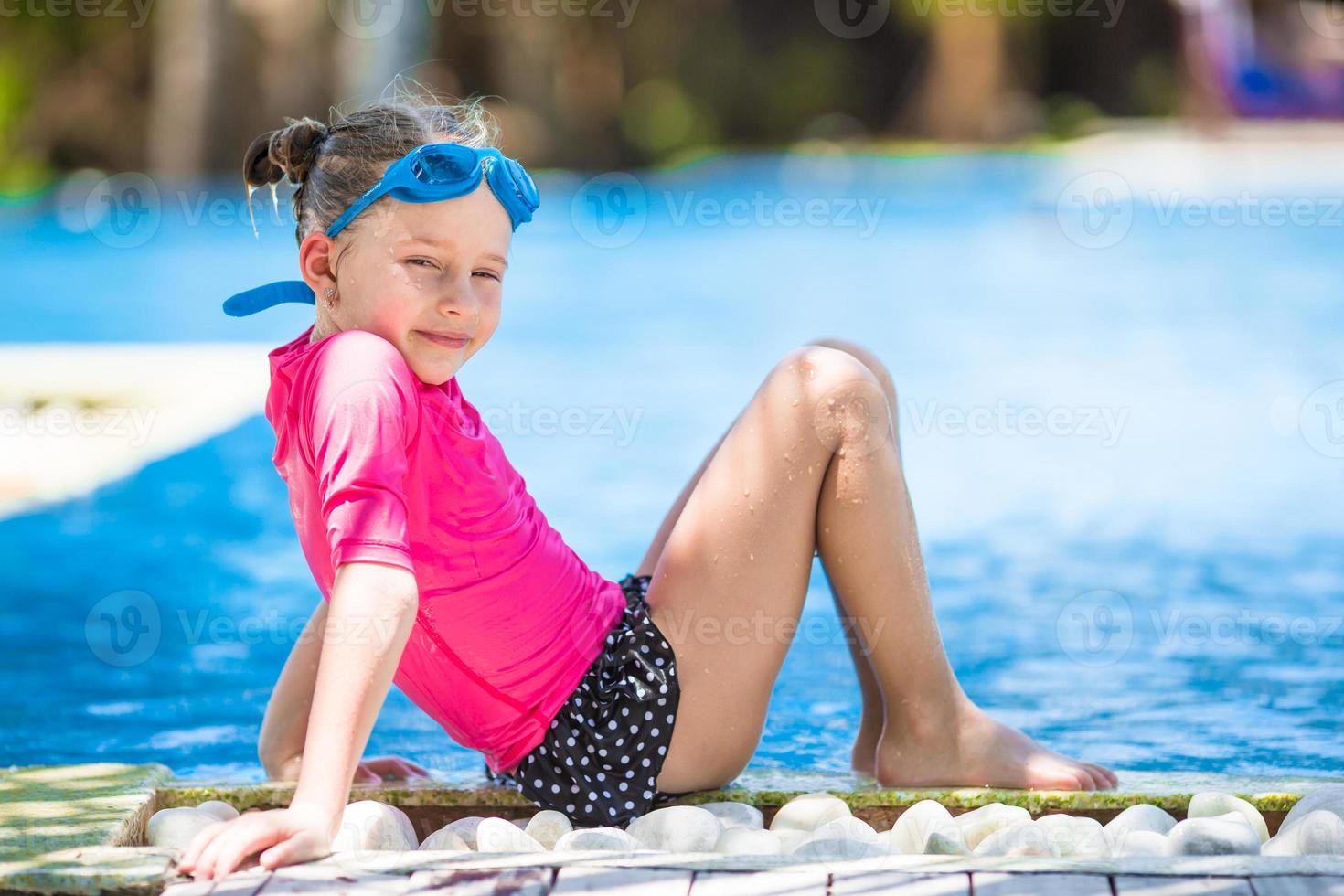 Adorable little girls at mask and goggles in outdoor swimming pool photo