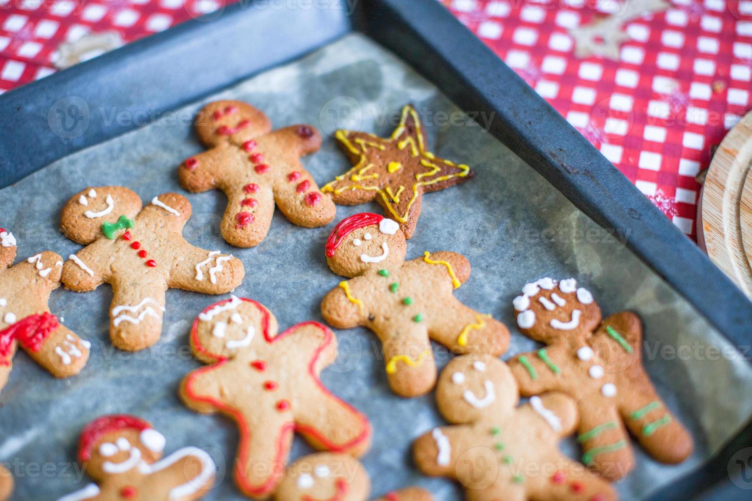 Raw gingerbread men with glaze on a baking sheet photo