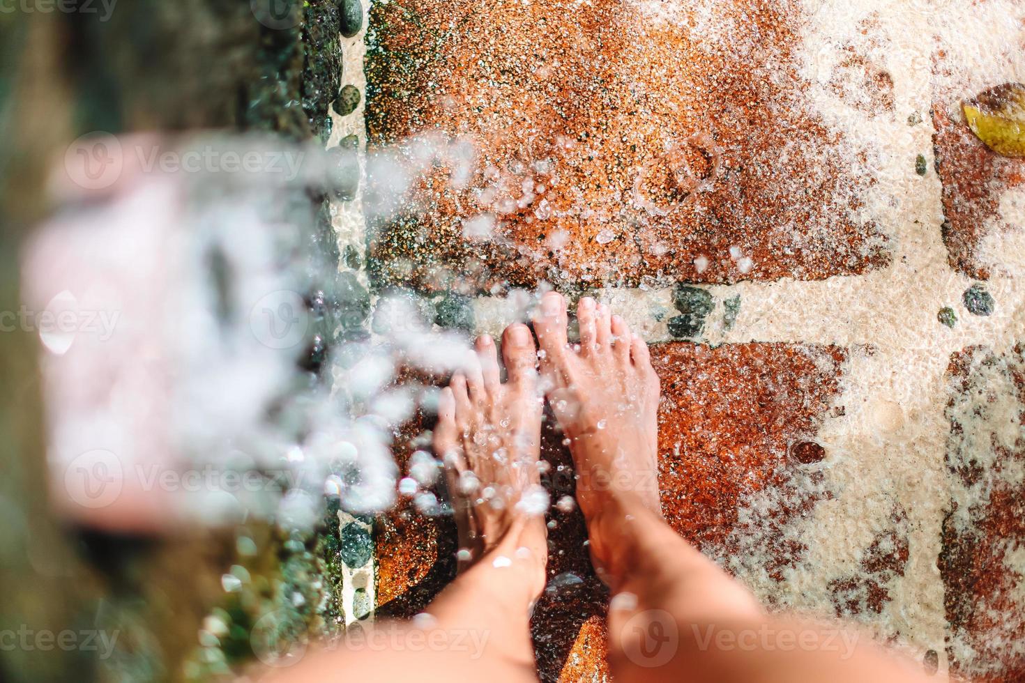 primer plano de las piernas femeninas bajo una ducha de playa foto