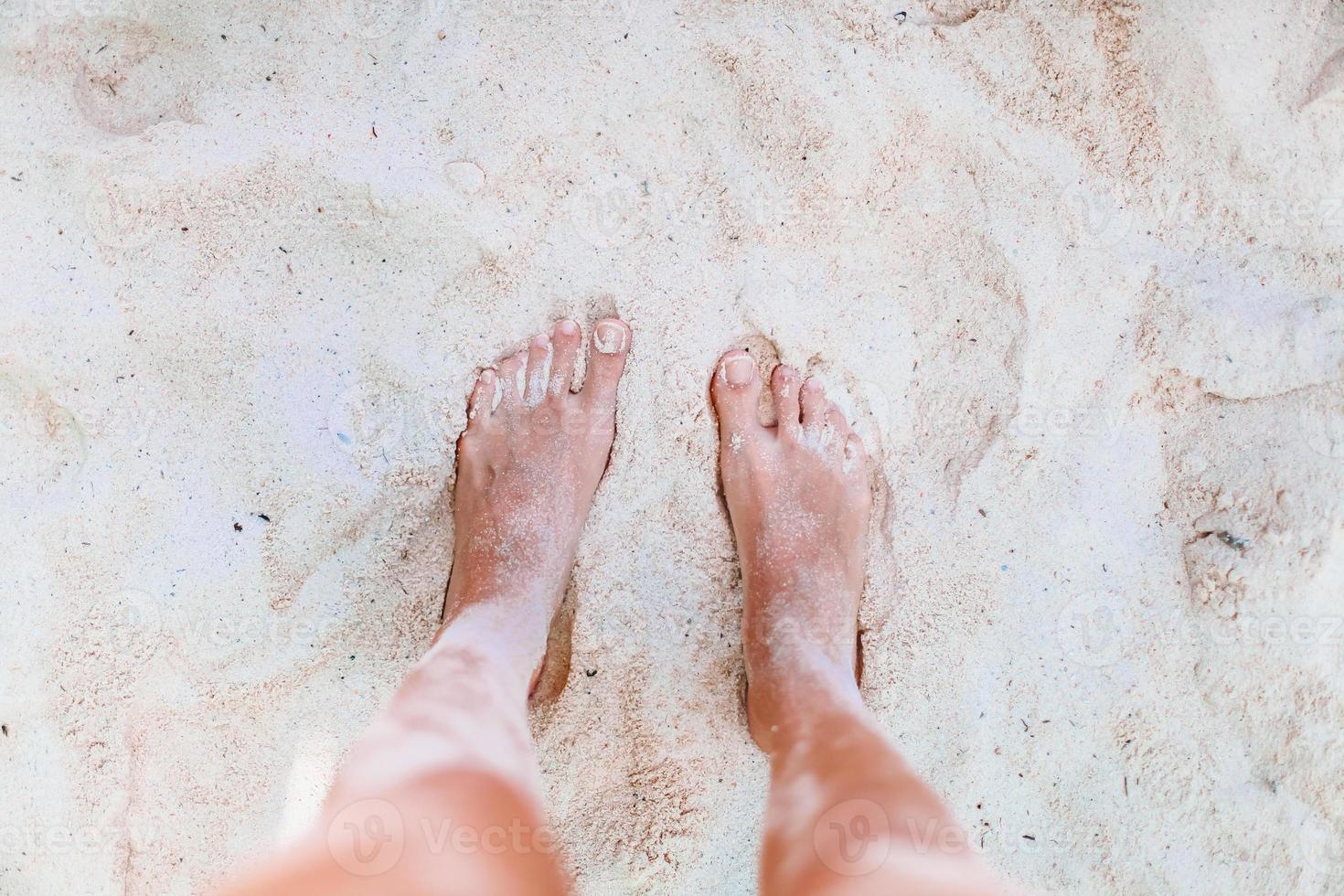 Young woman sunbathing on white beach. Legs. photo