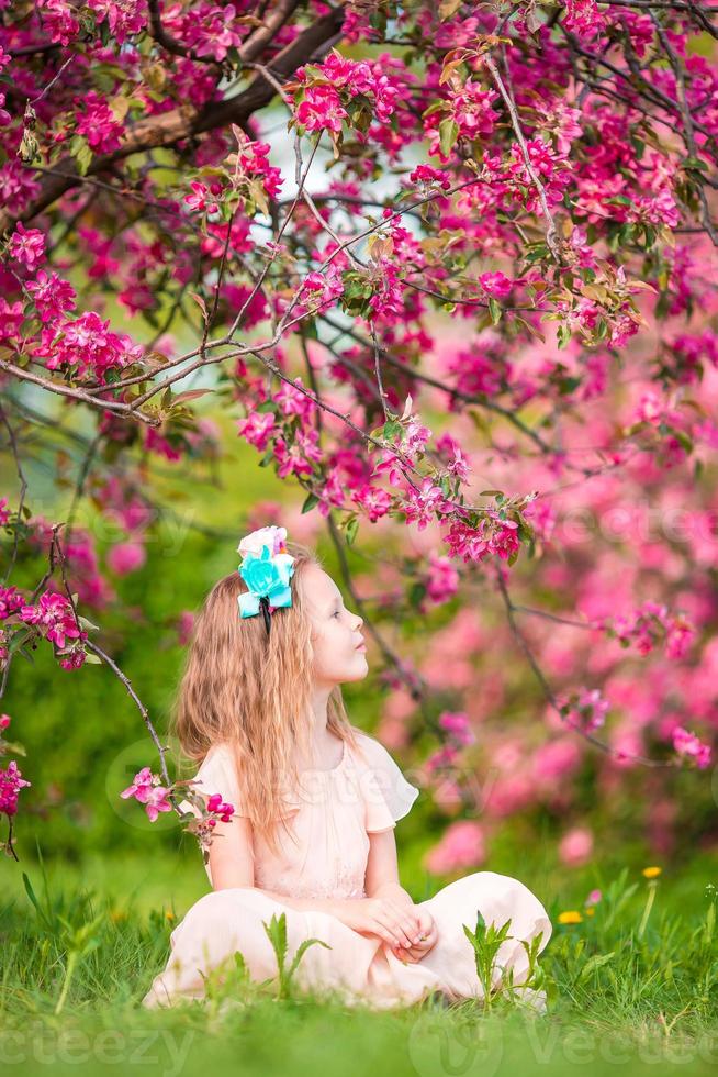 Adorable little girl in blooming apple garden on beautiful spring day photo