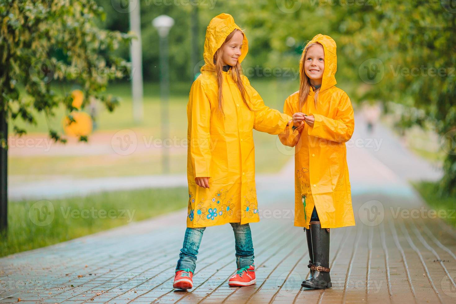Adorable little girls under the rain on warm spring day photo