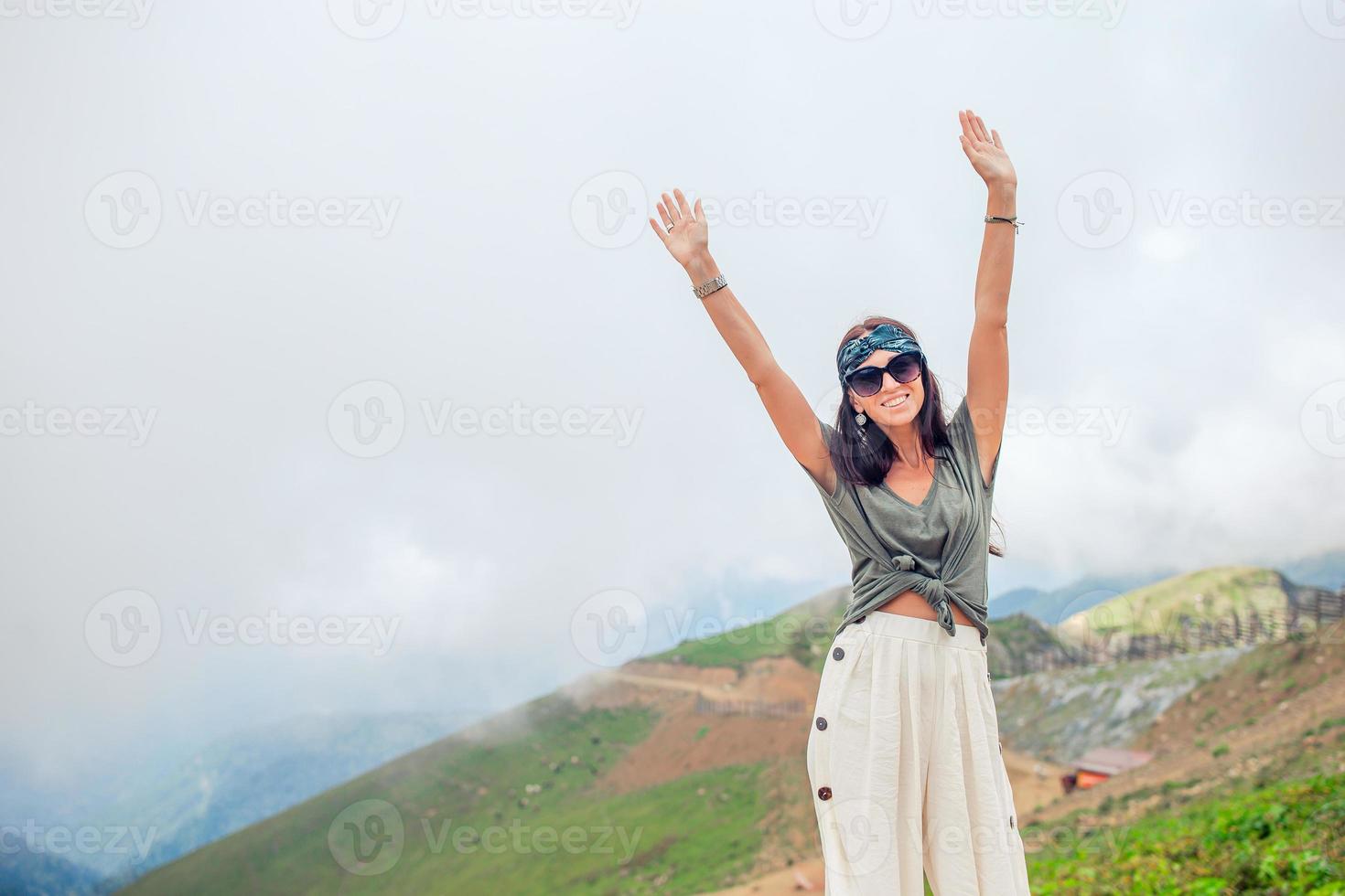 Beautiful happy young woman in mountains in the background of fog photo